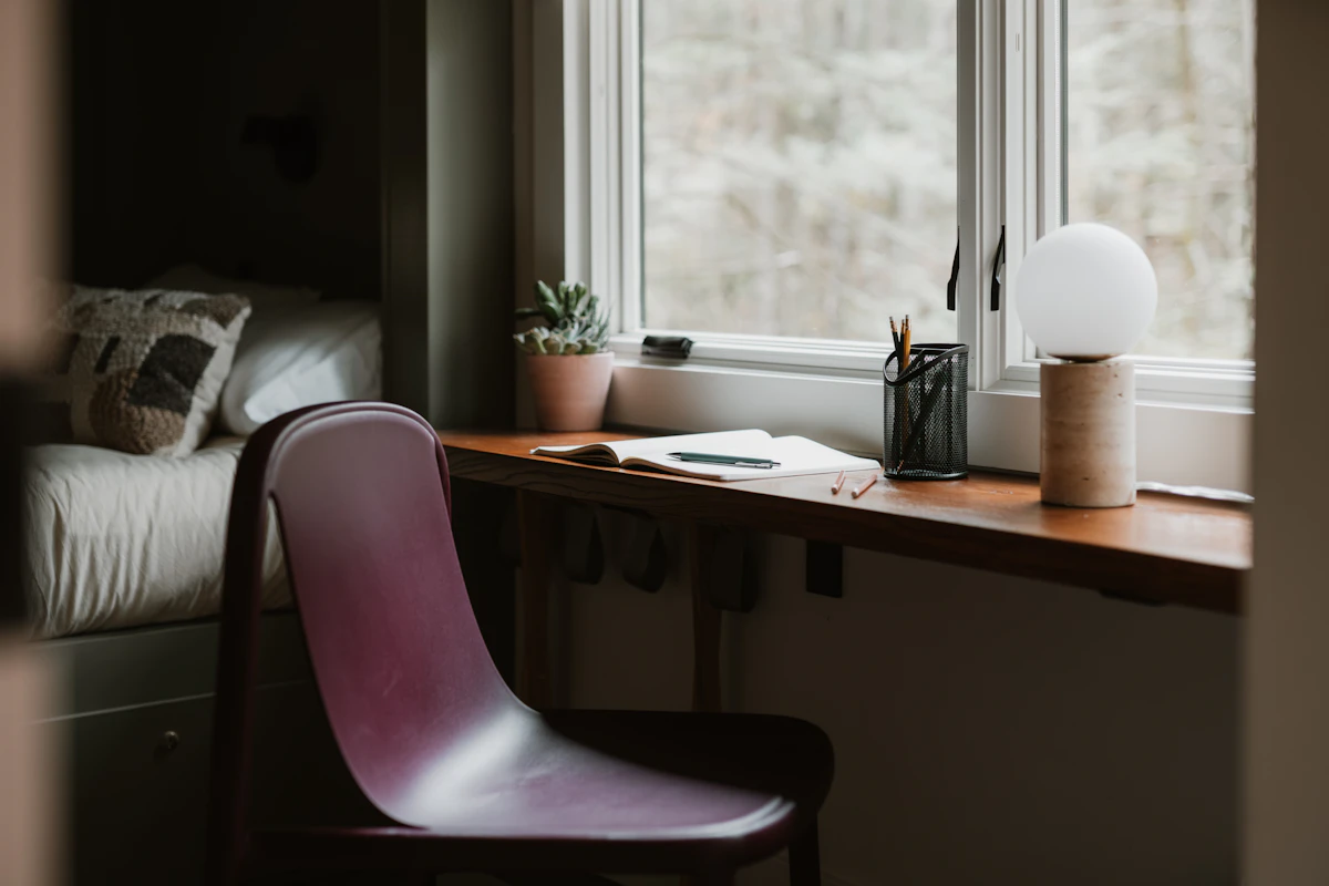 Small bedroom workspace with a desk positioned near a window for natural light