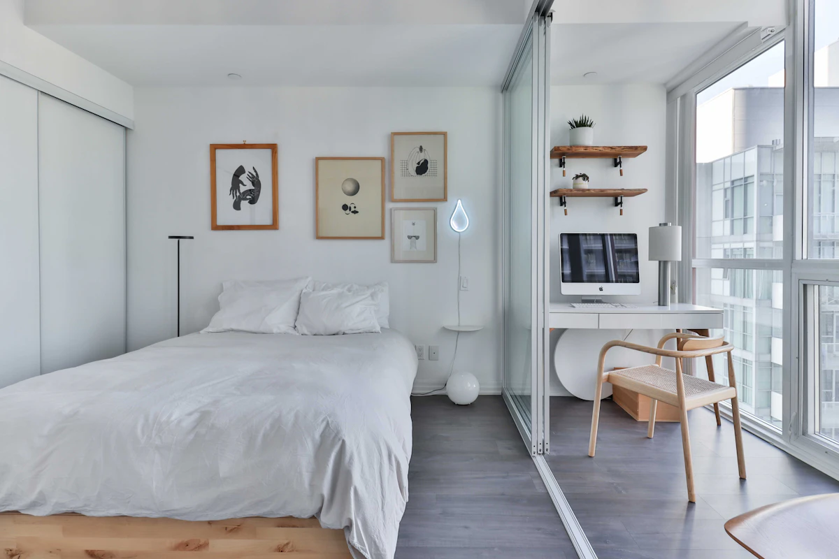 Small bedroom with bed, desk, chair, and window arranged in one compact layout