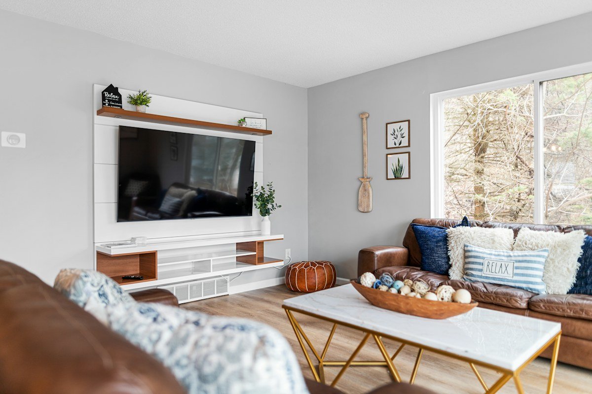 Living room with a wall-mounted TV, low floating-style media console, and balanced modern decor