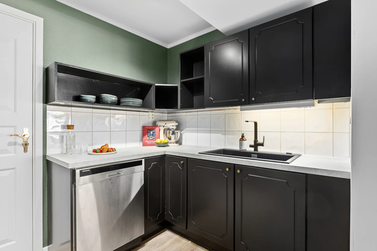 Compact kitchen with black cabinets, white counters and a bright tiled backsplash for high contrast