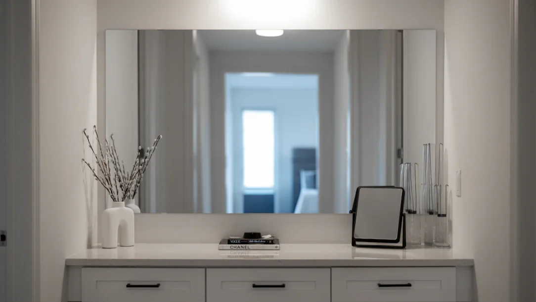 Small polished bedroom vanity with a large mirror, drawers, and compact seating