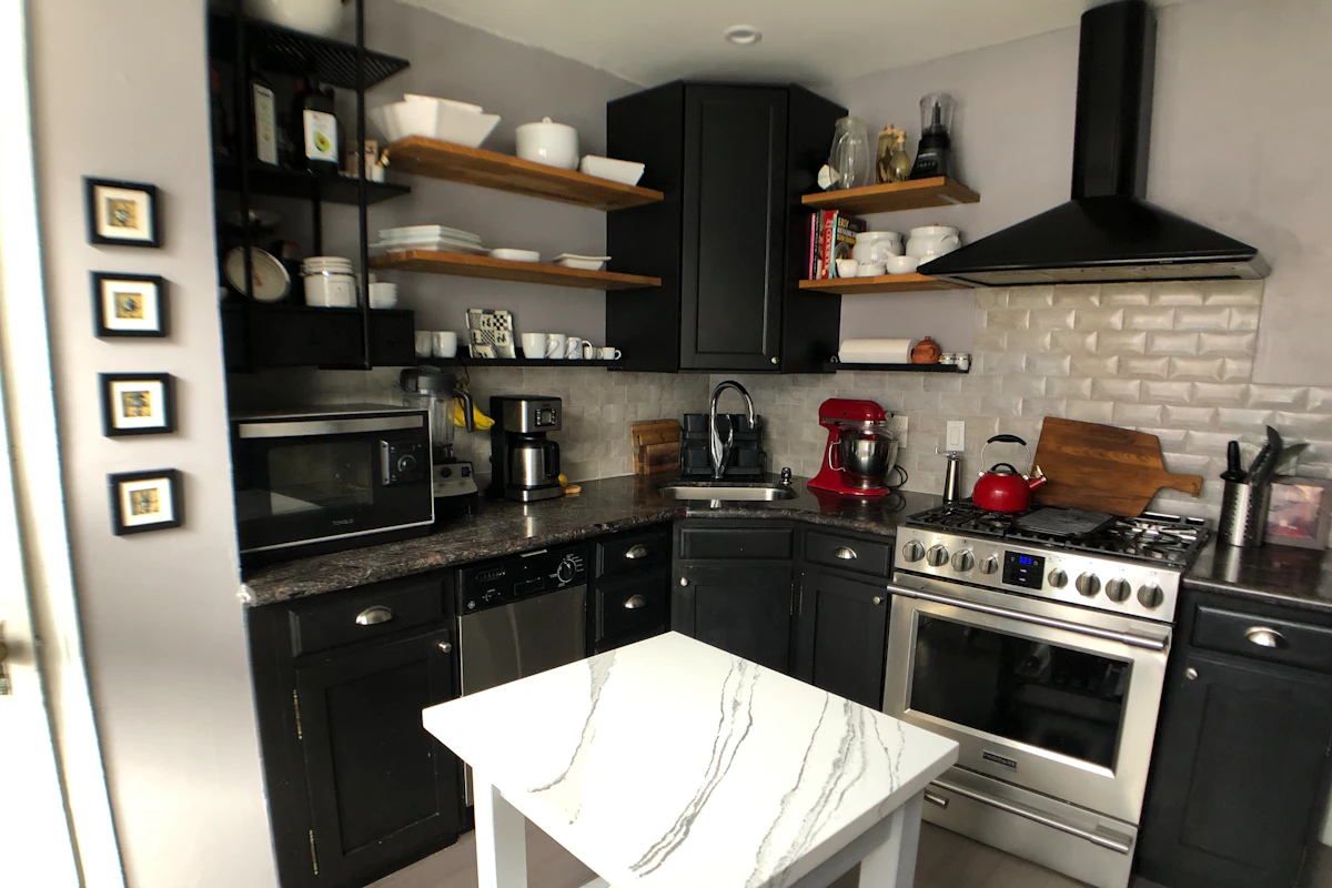 Small kitchen with black cabinets, open shelving and a white subway tile backsplash