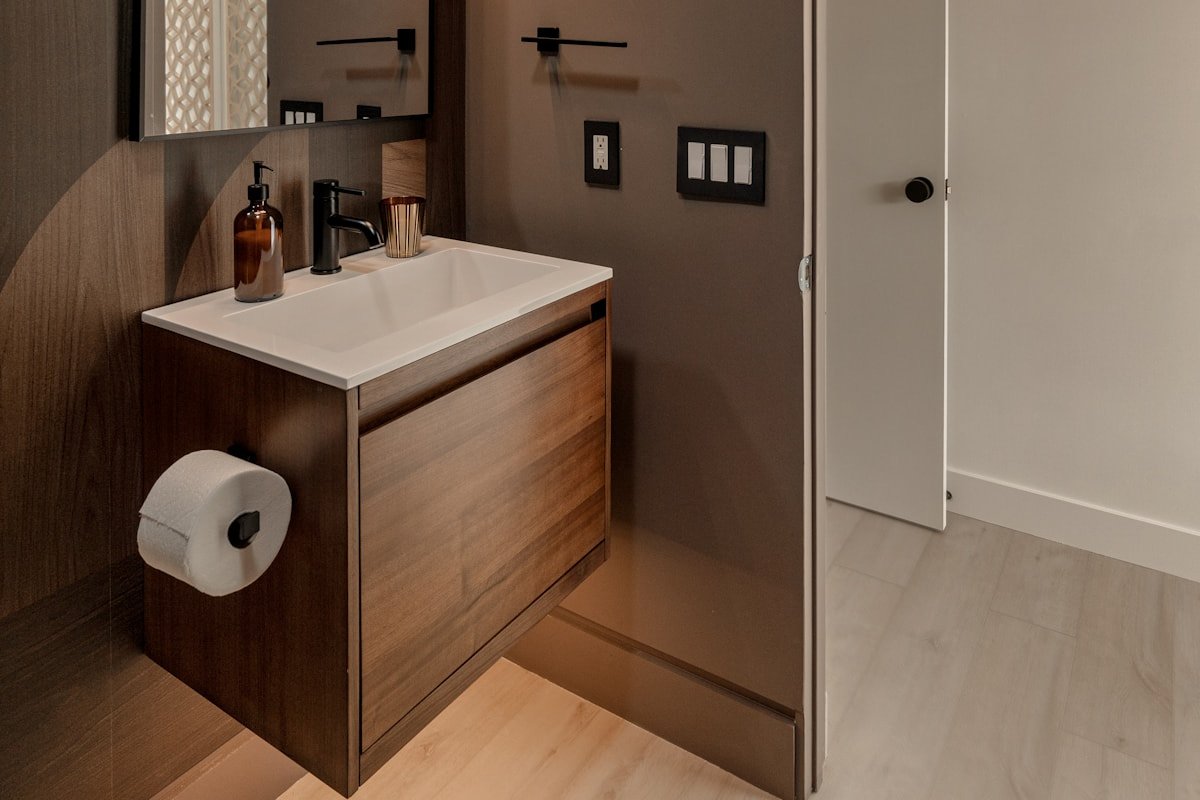 Bathroom with a wood vanity arched mirror and warm layered finishes