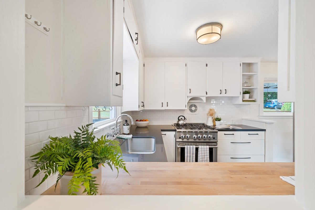 Compact kitchen with white cabinets, stove and calm light finishes