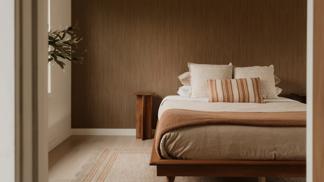 Cozy grown-up bedroom with warm brown wall, layered bedding and soft lighting