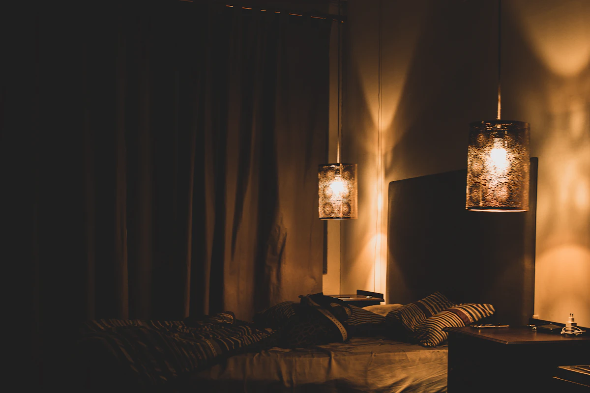 Dimly lit cozy bedroom with two warm bedside lamps