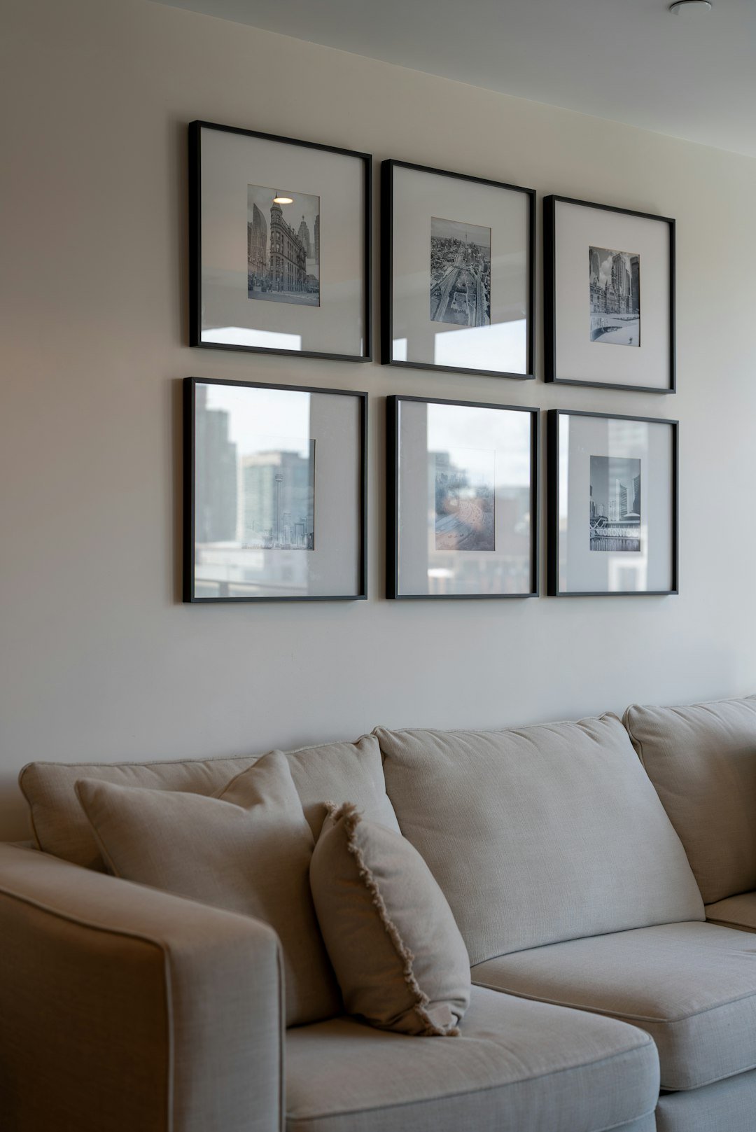 Gallery wall of six framed artworks above a light-colored sofa