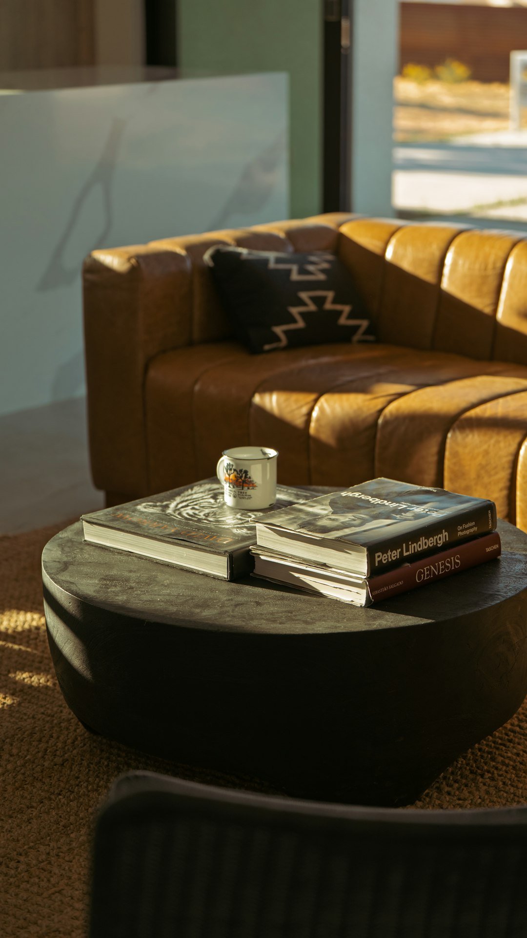 Lived-in living room coffee table with books and a mug beside a leather sofa