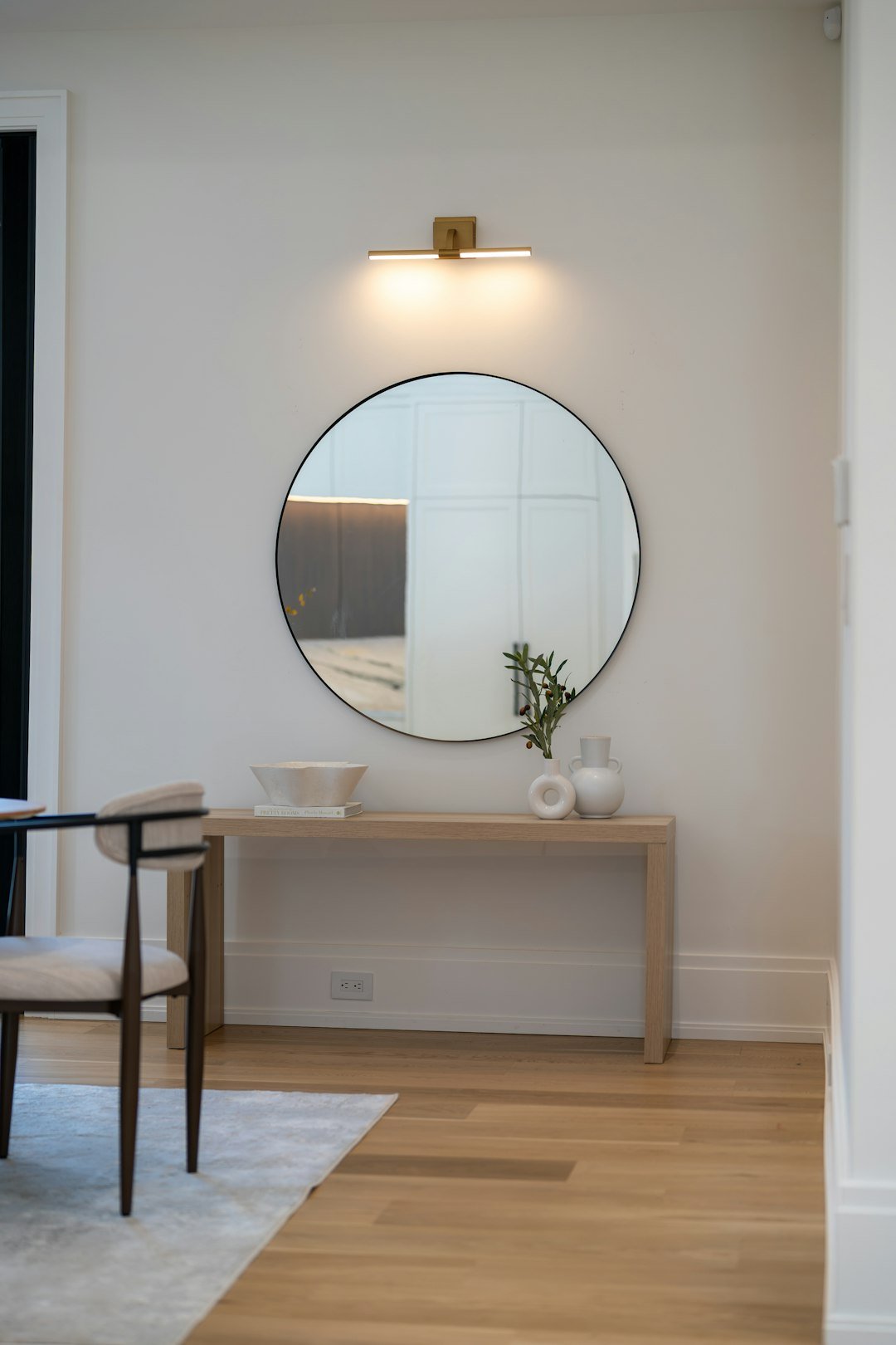 Round wall mirror above a wooden console table in an entryway