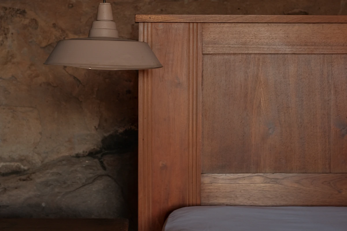 Warm bedroom with wooden headboard, bedside table and soft lamp