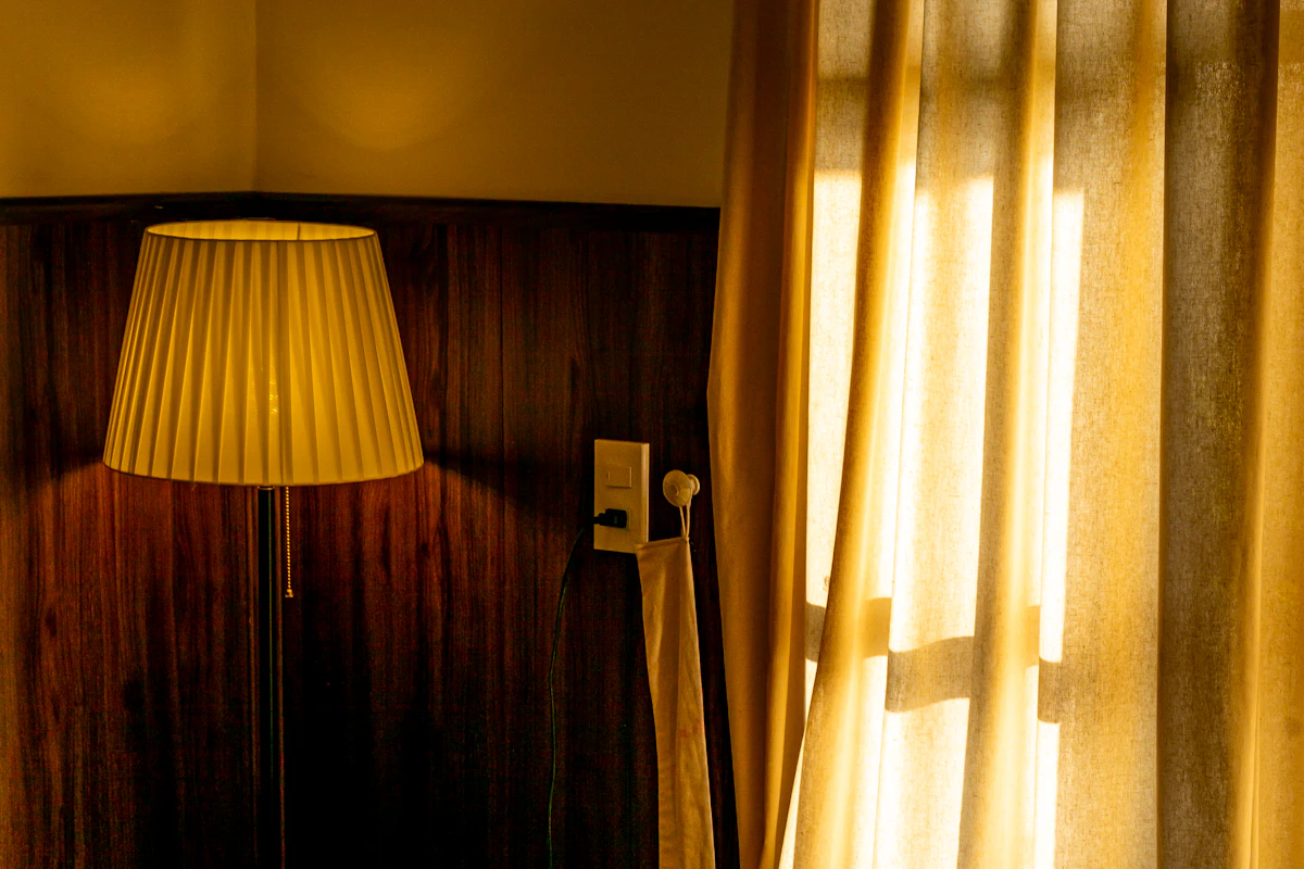 Warm daylight filtering through sheer curtains onto a cozy bed